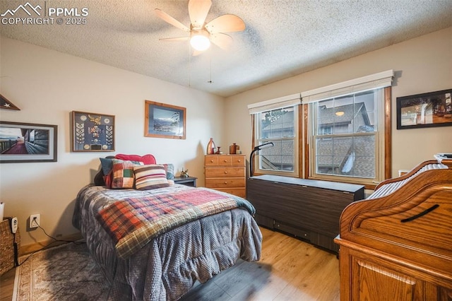 bedroom featuring ceiling fan, hardwood / wood-style floors, and a textured ceiling