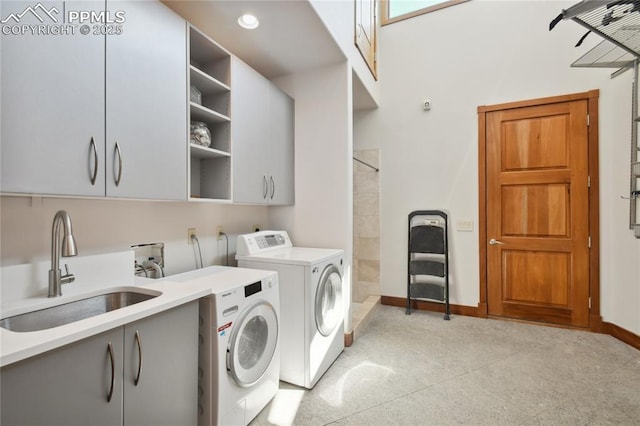 clothes washing area with cabinets, sink, and independent washer and dryer