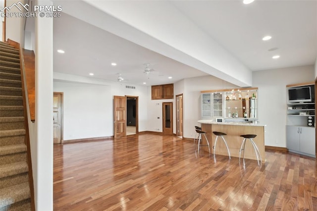 kitchen featuring light wood-type flooring, ceiling fan, and a breakfast bar area