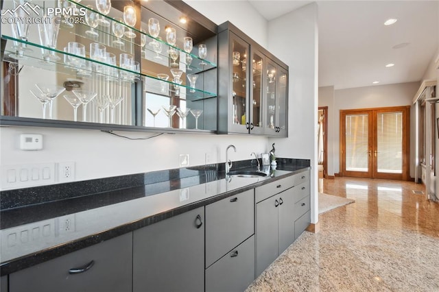 bar featuring sink, french doors, and dark stone countertops