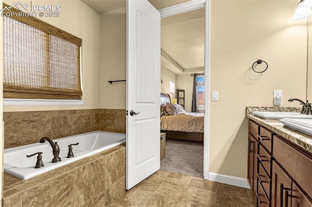 ensuite bathroom featuring connected bathroom, a sink, baseboards, a bath, and double vanity