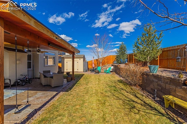 view of yard featuring ceiling fan, a fenced backyard, an outbuilding, a patio area, and a shed