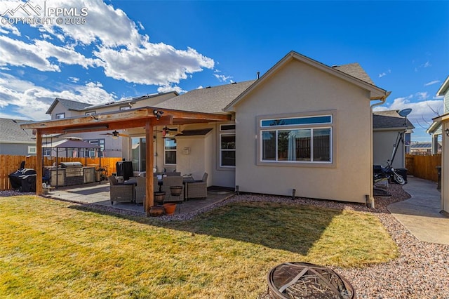 rear view of property with a yard, stucco siding, a patio area, ceiling fan, and a fenced backyard