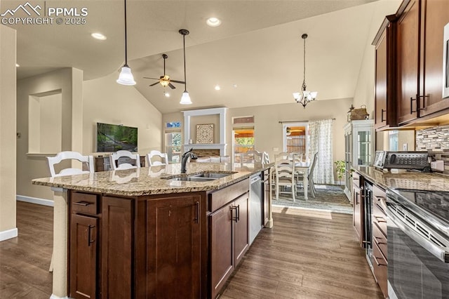 kitchen featuring stainless steel appliances, a kitchen island with sink, a sink, and hanging light fixtures