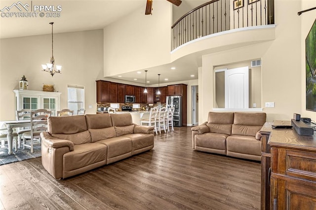 living room with visible vents, dark wood-style floors, ceiling fan with notable chandelier, high vaulted ceiling, and recessed lighting