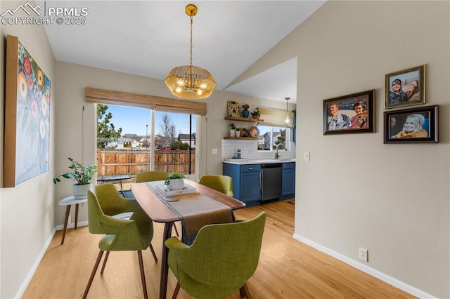 dining room featuring vaulted ceiling, sink, a notable chandelier, and light wood-type flooring