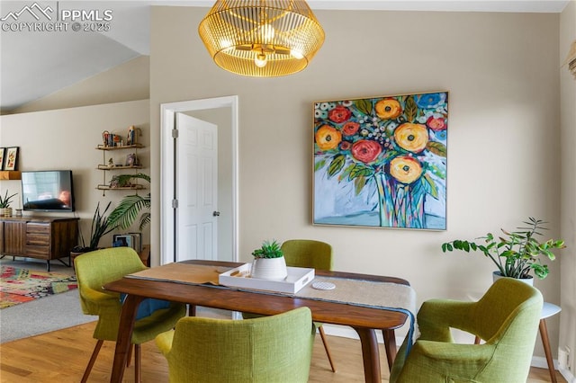 dining area featuring wood-type flooring and vaulted ceiling