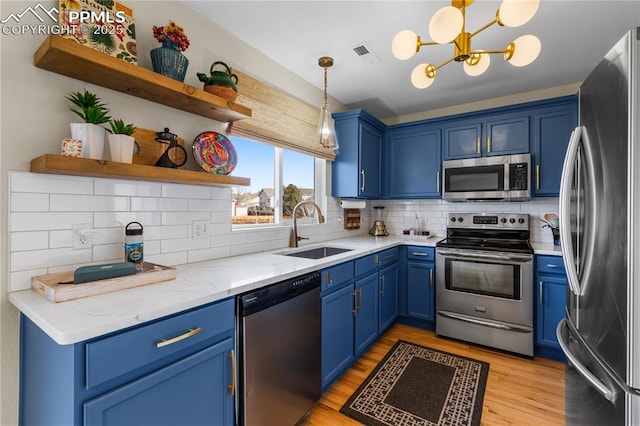 kitchen featuring stainless steel appliances, blue cabinets, sink, and hanging light fixtures