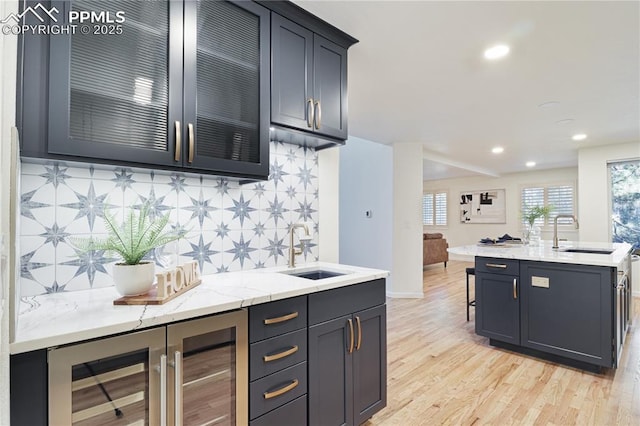 kitchen with sink, wine cooler, backsplash, and light hardwood / wood-style flooring