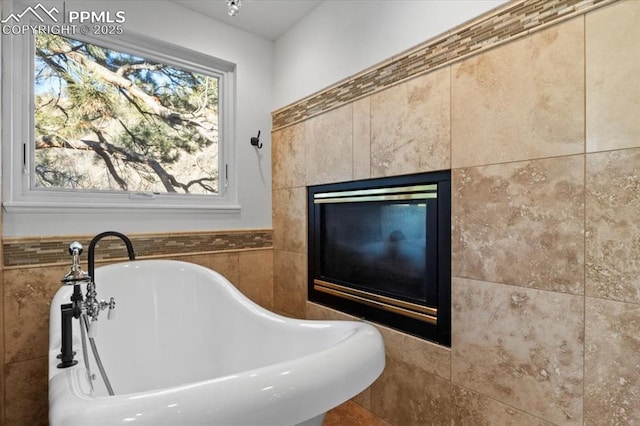 bathroom with a washtub, a fireplace, and plenty of natural light