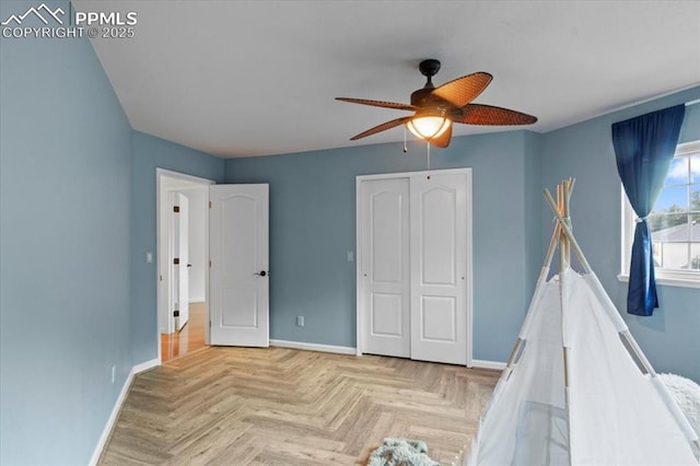 unfurnished bedroom with ceiling fan, light parquet flooring, and a closet