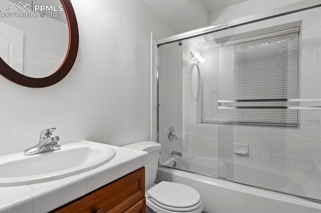 full bathroom featuring vanity, combined bath / shower with glass door, and toilet