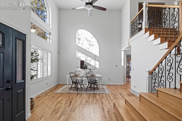 foyer featuring hardwood / wood-style floors, a towering ceiling, and ceiling fan