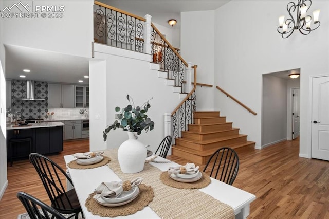 dining area with hardwood / wood-style flooring, a towering ceiling, and a notable chandelier