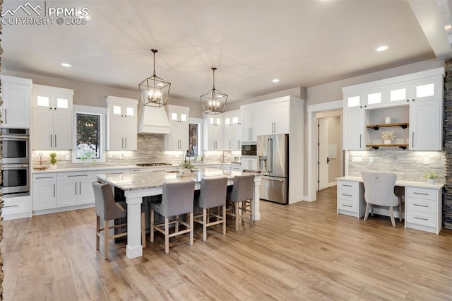 kitchen featuring a kitchen island, appliances with stainless steel finishes, a breakfast bar area, white cabinets, and hanging light fixtures