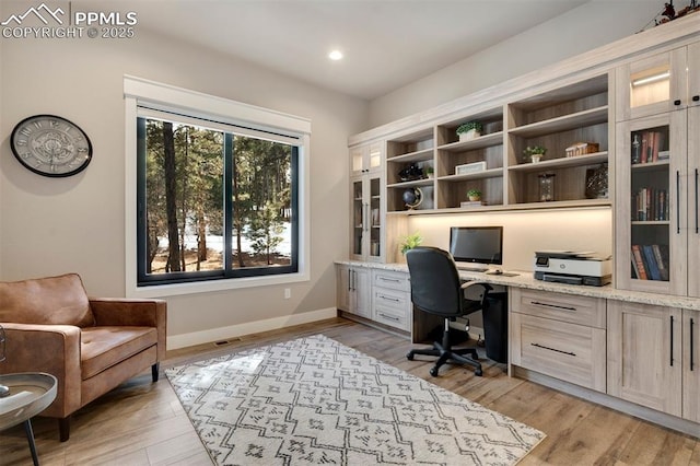 office with built in desk and light hardwood / wood-style flooring