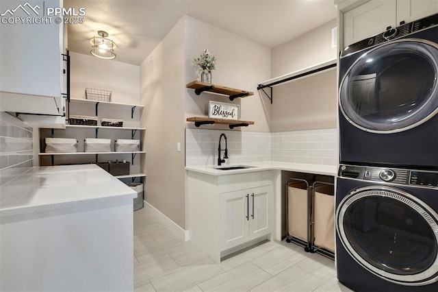 clothes washing area with stacked washing maching and dryer and sink