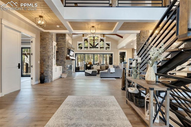 foyer featuring an inviting chandelier, a towering ceiling, beamed ceiling, and hardwood / wood-style flooring