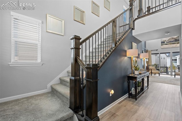 stairway with a towering ceiling and hardwood / wood-style floors