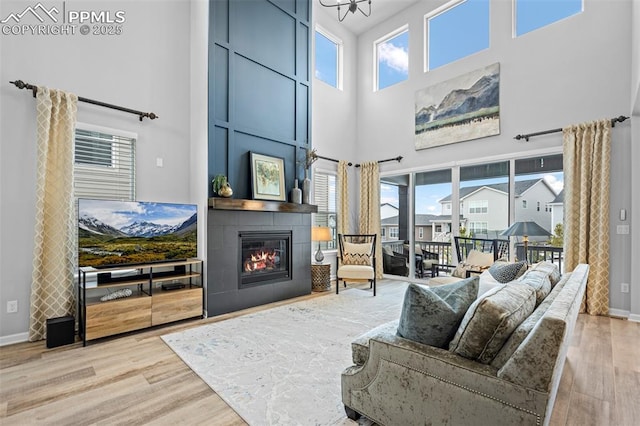 living room featuring a large fireplace, a wealth of natural light, light hardwood / wood-style floors, and a towering ceiling