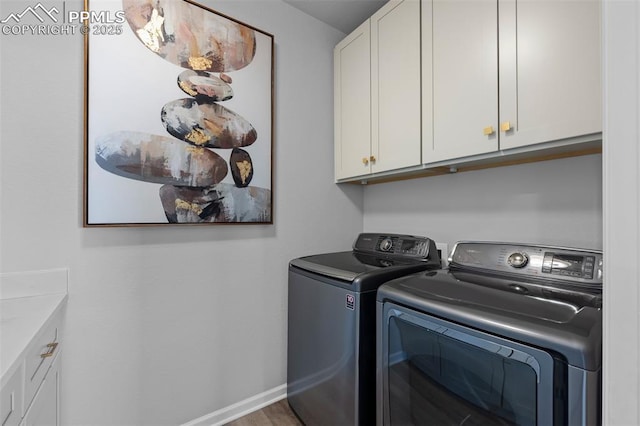 clothes washing area with separate washer and dryer and cabinets