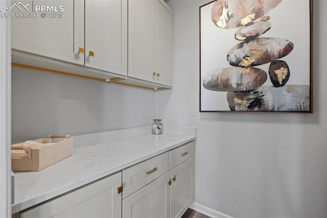 bar featuring light stone countertops and white cabinets