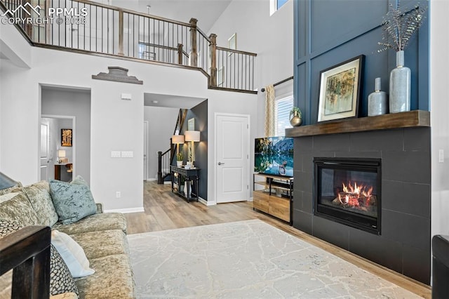 living room featuring a large fireplace, a towering ceiling, and light wood-type flooring