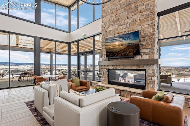 living room featuring a towering ceiling, a healthy amount of sunlight, and a multi sided fireplace