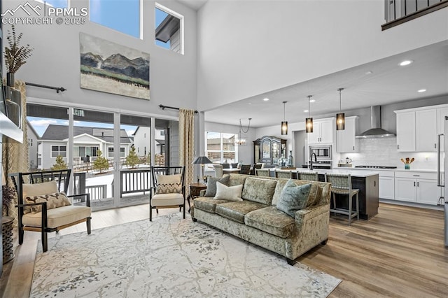 living room featuring an inviting chandelier, sink, and light hardwood / wood-style flooring