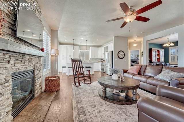 living room with a fireplace, a wealth of natural light, light hardwood / wood-style flooring, and a textured ceiling