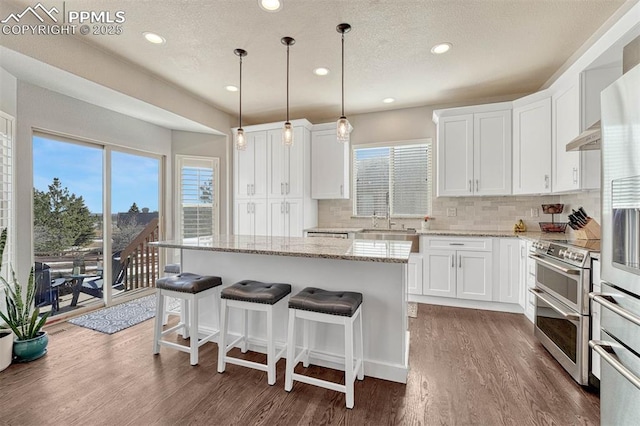 kitchen featuring white cabinetry, range with two ovens, sink, and a kitchen island