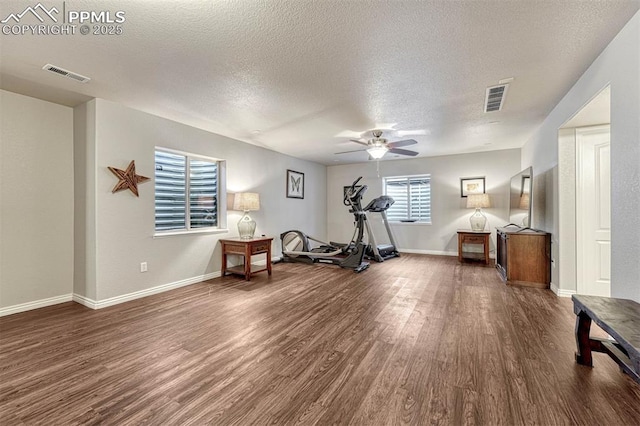 workout room with ceiling fan, dark hardwood / wood-style flooring, and a textured ceiling