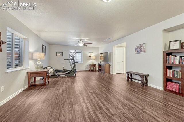 workout room featuring ceiling fan, dark hardwood / wood-style flooring, and a textured ceiling