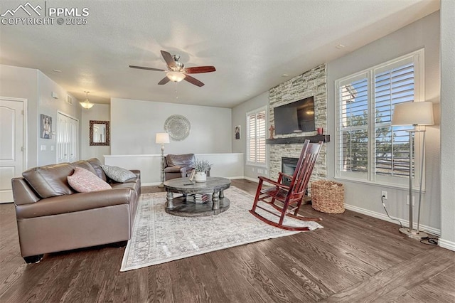 living room featuring ceiling fan, dark wood-type flooring, a textured ceiling, and a fireplace