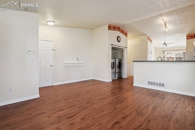 unfurnished living room with lofted ceiling, washer and dryer, and dark hardwood / wood-style floors