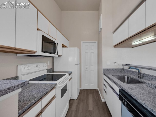 kitchen featuring sink, white cabinets, dark hardwood / wood-style flooring, dark stone counters, and white appliances