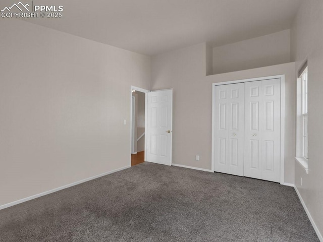 unfurnished bedroom with dark carpet and a closet