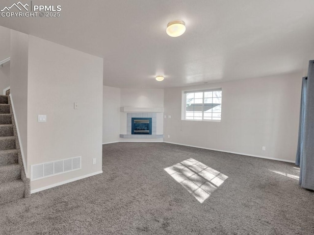 unfurnished living room with a tiled fireplace and carpet