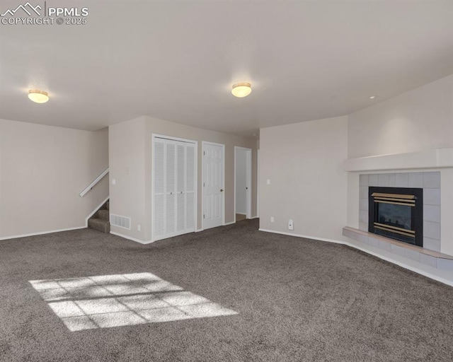 unfurnished living room with a tile fireplace and carpet flooring