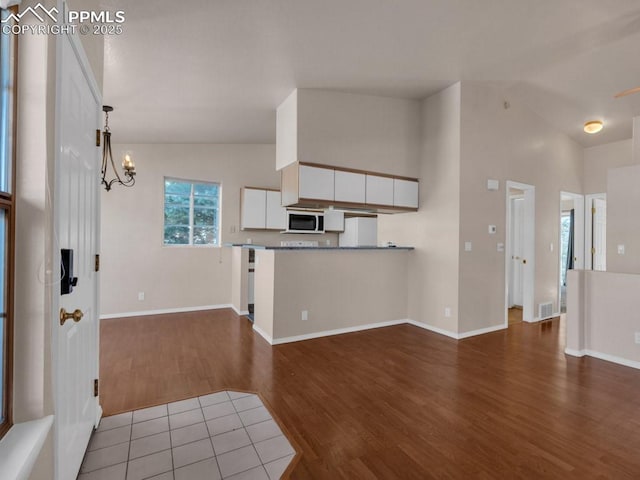 kitchen featuring high vaulted ceiling, dark wood-type flooring, a chandelier, and fridge