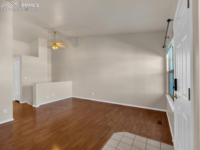 empty room with lofted ceiling, hardwood / wood-style floors, and ceiling fan