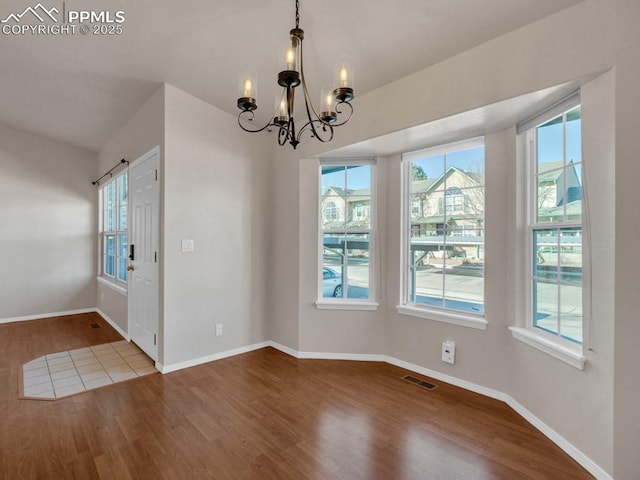 unfurnished dining area with wood-type flooring and a chandelier