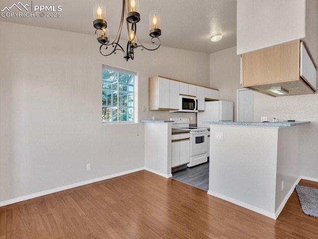 kitchen featuring white cabinetry, hanging light fixtures, dark hardwood / wood-style floors, a notable chandelier, and white appliances