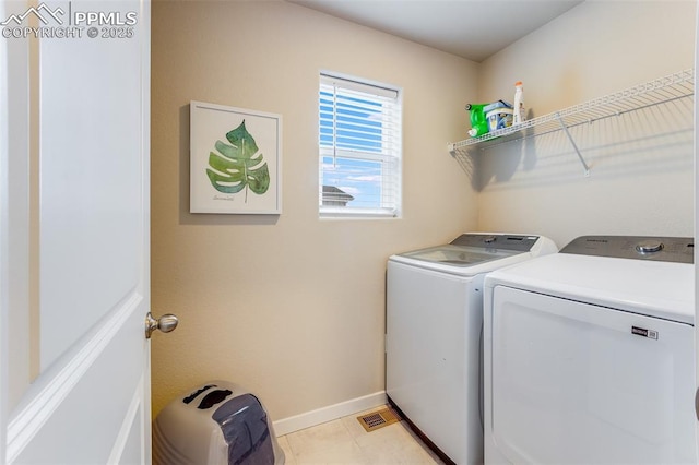 laundry room with washing machine and dryer and light tile patterned floors