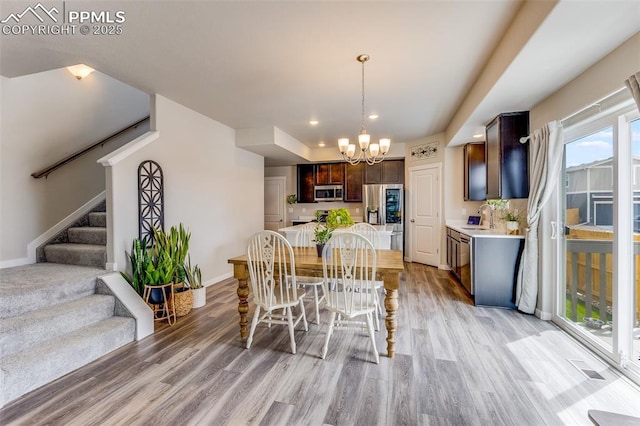 dining room with sink, an inviting chandelier, and light hardwood / wood-style floors