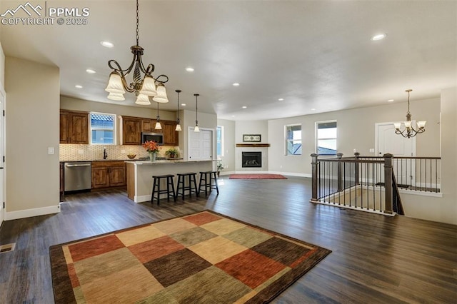 interior space with pendant lighting, appliances with stainless steel finishes, a center island, and a chandelier