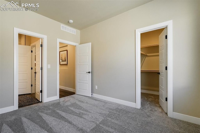 unfurnished bedroom featuring a spacious closet, dark carpet, and a closet