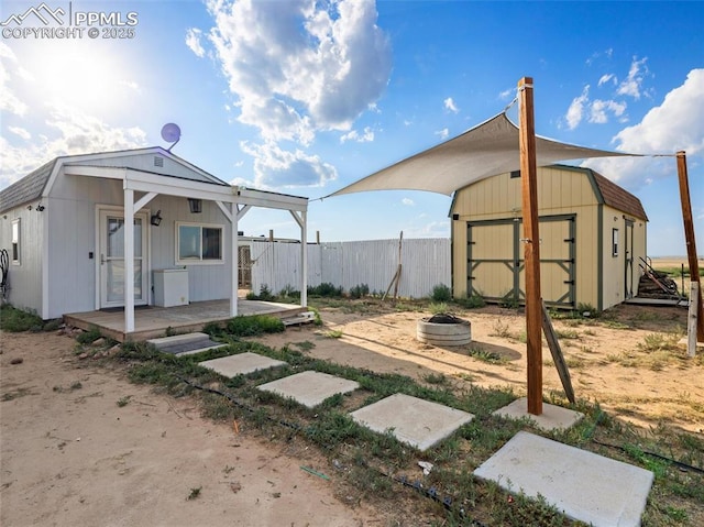 view of yard featuring a fire pit, a storage unit, an outdoor structure, and fence