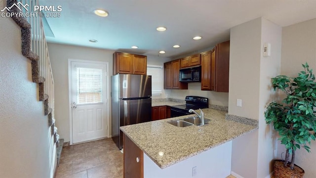 kitchen with light tile patterned flooring, black appliances, sink, light stone counters, and kitchen peninsula