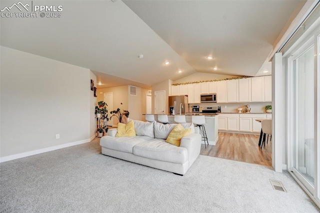 living area featuring baseboards, visible vents, vaulted ceiling, and light colored carpet